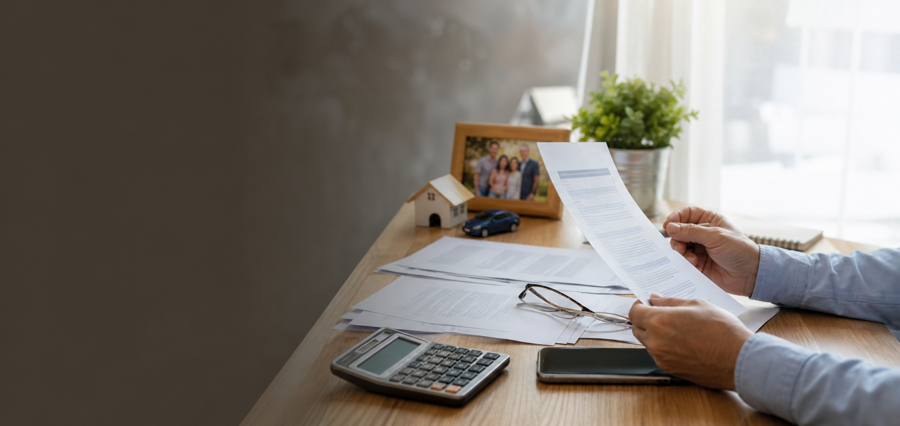 Hands reviewing insurance documents, a calculator, and household paperwork on a desk
